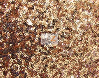 May include: A close-up of a fabric with a shimmering, iridescent finish. The fabric is covered in small, round sequins that are arranged in a random pattern. The sequins are a mix of gold and copper colors, creating a warm and inviting look.