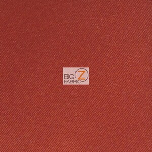May include: A close-up of a solid rust-colored fabric with a subtle diagonal weave. The fabric is smooth and has a slight sheen.