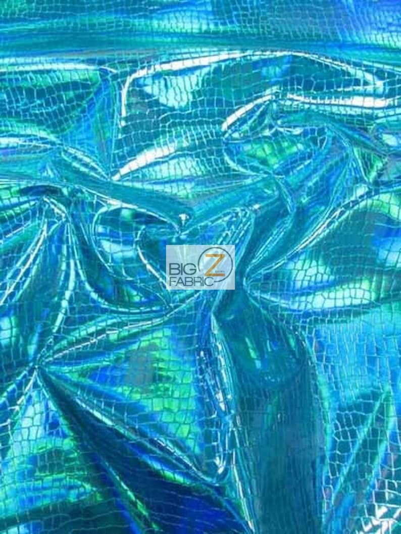 May include: A close-up of iridescent blue fabric with a crocodile skin pattern. The fabric is shiny and has a holographic effect.