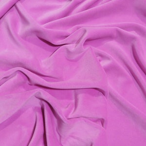 May include: A close-up of a bright pink fabric, possibly velvet, with a soft, flowing texture. The material is draped and folded, creating shadows and highlights. The folds and creases add depth and visual interest to the image, highlighting the fabric's luxurious appearance.