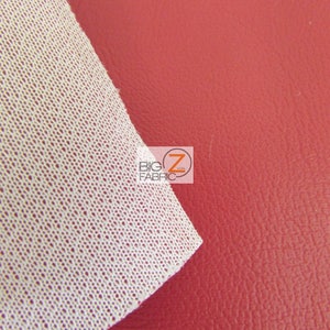 May include: Close-up of a red faux leather fabric with a white backing. The fabric has a textured surface and is ideal for upholstery or crafting projects.