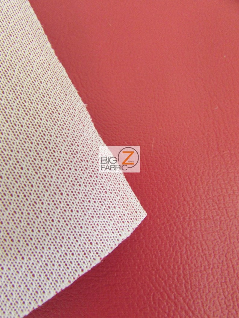 May include: Close-up of a red faux leather fabric with a white backing. The fabric has a textured surface and is ideal for upholstery or crafting projects.