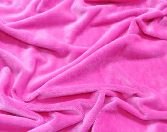 Puede incluir: Primer plano de una tela suave y rosa con una textura suave y aterciopelada. La tela está drapeada y doblada, creando un aspecto lujoso y acogedor.
