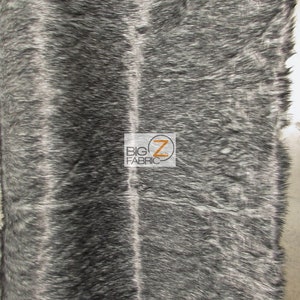 Może przedstawiać: Czarno-biały materiał z imitacji futra o długim włosiu. Materiał ma subtelny połysk i jest miękki w dotyku.