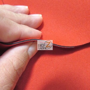 May include: Close-up of a bright red fabric with a black edge. The fabric is smooth and has a slight sheen. The text "BIG Z FABRIC" is visible in the image.