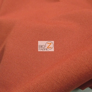 May include: A close-up of a rust-colored fabric with a subtle texture. The fabric is folded and has a slight sheen.