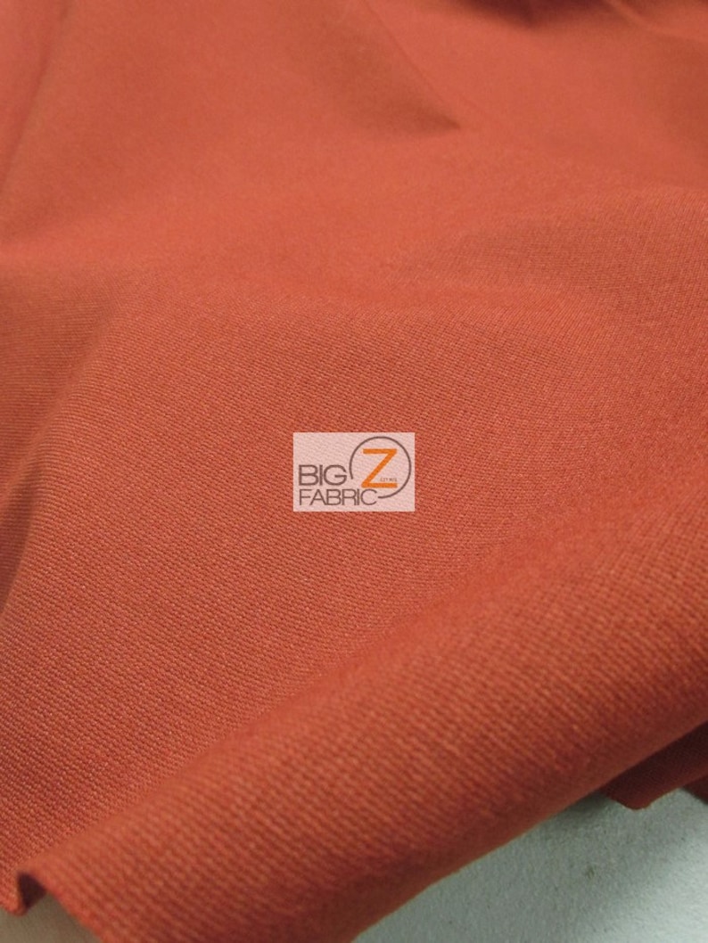 May include: A close-up of a rust-colored fabric with a subtle texture. The fabric is folded and has a slight sheen.