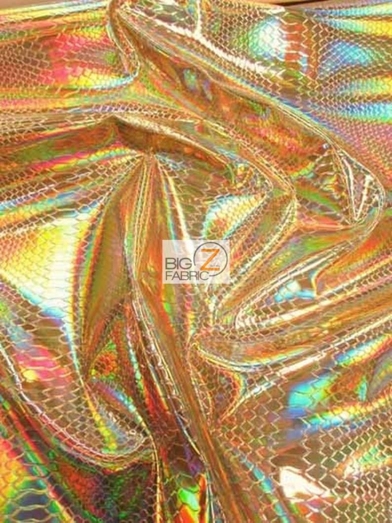 Pu&ograve; includere: Primo piano di un tessuto dorato iridescente con un motivo a pelle di serpente. Il tessuto ha una finitura olografica ed &egrave; testurizzato.
