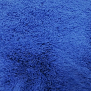 May include: A close-up of a soft, blue faux fur fabric. The fabric has a fluffy texture and a deep blue color.
