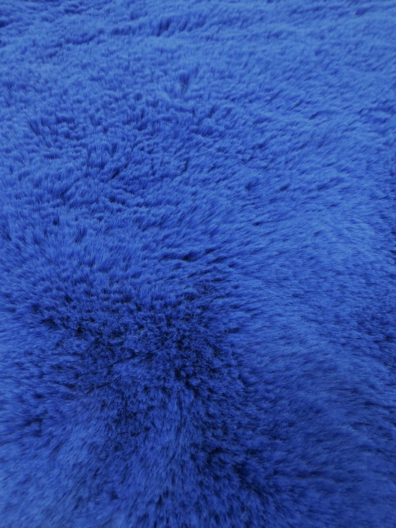 May include: A close-up of a soft, blue faux fur fabric. The fabric has a fluffy texture and a deep blue color.