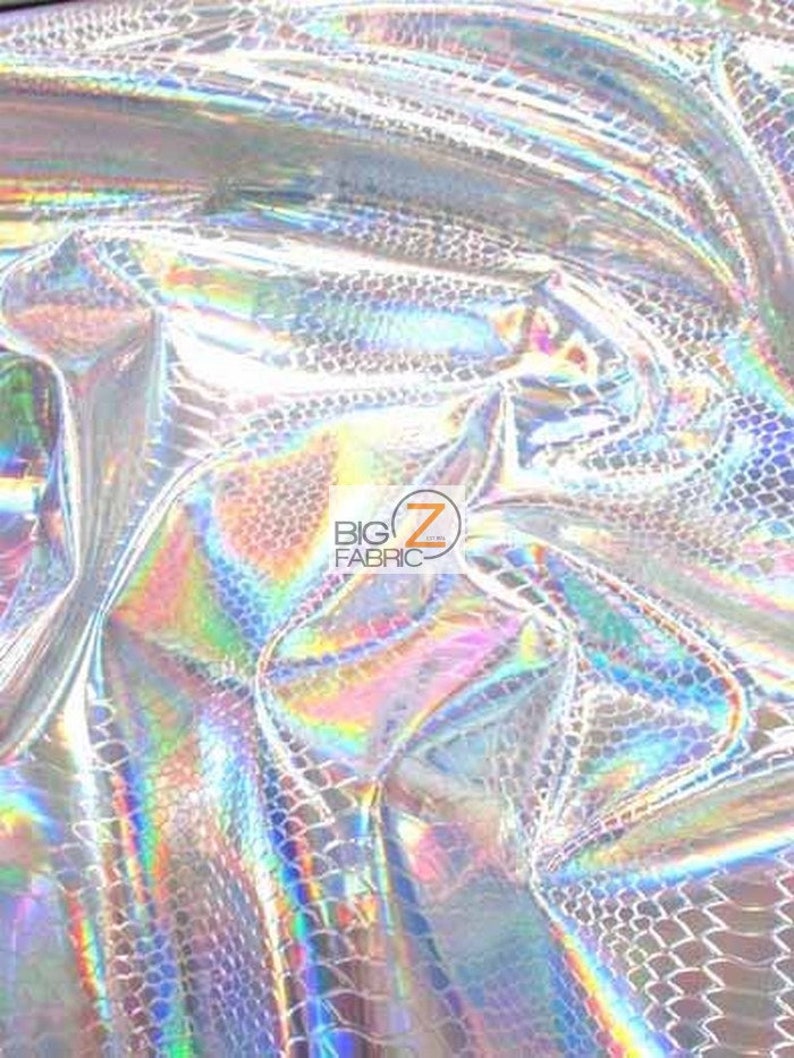 Pu&ograve; includere: Primo piano di un tessuto argentato iridescente con un sottile motivo a squame. Il tessuto ha una finitura olografica che brilla con colori arcobaleno.