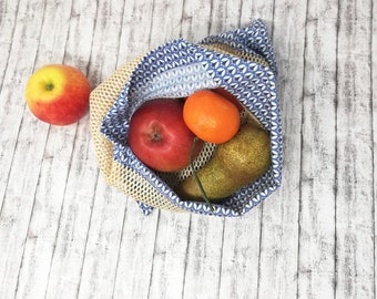 May include: A blue and white patterned reusable produce bag with a red apple, a green pear, and an orange mandarin orange inside.
