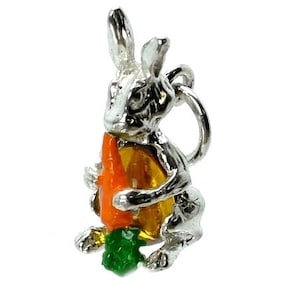 May include: A silver-colored bunny charm holding an orange carrot with yellow and green accents. The bunny has detailed features and a loop for attaching to a bracelet or necklace. The charm is a cute, whimsical accessory.