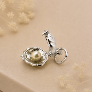 Charm de perla en ostra de plata esterlina que se abre para revelar una perla cultivada.