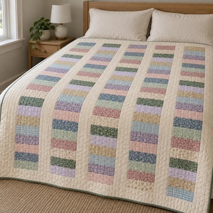May include: A quilt featuring vertical columns of rectangular fabric patches in various floral and gingham patterns. The colors include soft pink, sage green, light blue, and lavender, separated by solid cream-colored fabric strips.