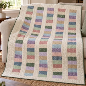 May include: A rectangular quilt featuring vertical columns of alternating fabric patches. The patches display various floral and gingham patterns in shades of pink, blue, green, purple, and tan, separated by solid cream-colored fabric strips.