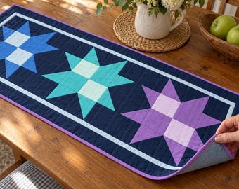 Patroon voor een tafelloper/quilt met sterrenmotief (PDF), noorderlicht, blauw turkoois en paars patchwork, geïllustreerd prototype
