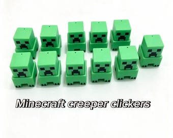 May include: Eleven green square-shaped Minecraft creeper clickers arranged in two rows. Each small plastic figure features a pixelated black face with eyes and a mouth. The text "Minecraft creeper clickers" is printed below the figures.