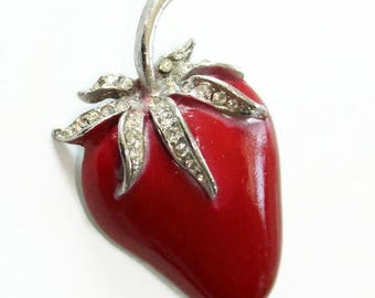 May include: A red enamel strawberry brooch with silver tone leaves and rhinestones.