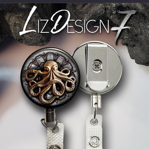 May include: A silver retractable badge reel with a black and gold octopus design. The reel has a heavy duty steel cable and a clip for attaching to clothing. "Heavy Duty Badge Reel with Steel Cable" is written below the reel.