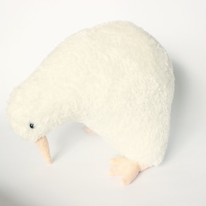 May include: A plush, cream-colored kiwi bird toy. The soft toy has a long, curved beak, small black eyes, and tiny feet. The kiwi is a flightless bird native to New Zealand. The toy is designed to resemble the bird.