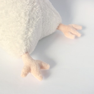 May include: A plush white chicken toy with soft, fluffy feathers. The chicken has light pink feet with three toes. The toy is designed to be soft and cuddly, perfect for children or as a decorative item.