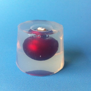 May include: A clear plastic mold with a red Christmas ornament inside.