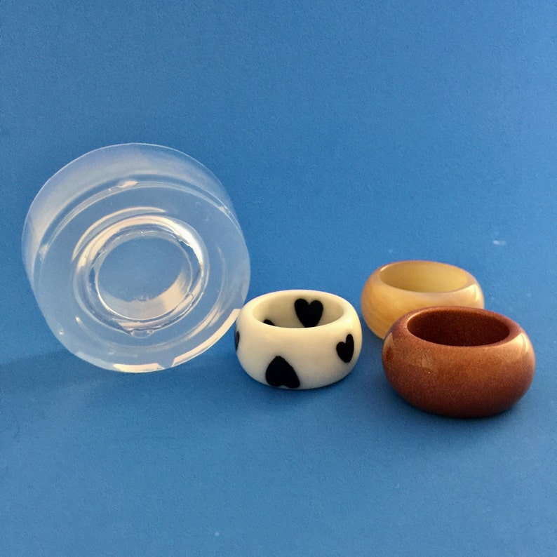 May include: Three resin rings, one with a white base and black heart pattern, one with a light brown base, and one with a light yellow base. A clear silicone mold is also shown.