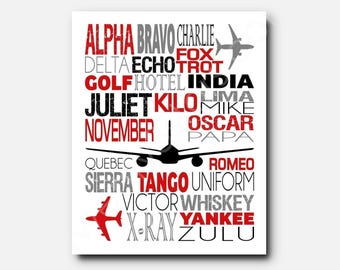 May include: A white rectangular print featuring the aviation phonetic alphabet from Alpha to Zulu in red, black, and gray text. The design includes two silhouettes of airplanes, one in black and one in red, arranged among the words.