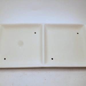 May include: A rectangular, off-white ceramic divided serving dish. The dish has a slightly trapezoidal shape with rounded corners and four small holes. The surface is smooth with a subtle sheen.