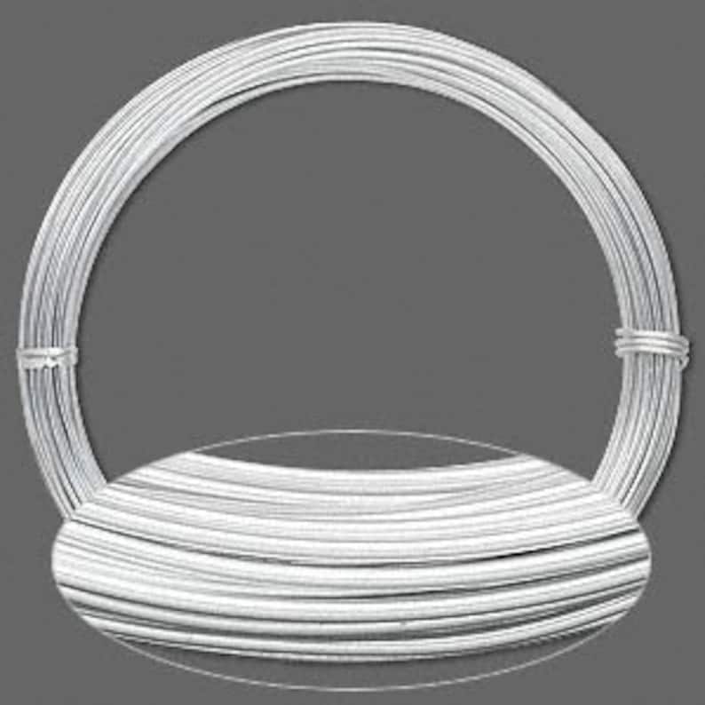 May include: A tightly wound coil of silver-coloured wire, suitable for crafts or jewellery making. The wire is smooth and reflective, with a neutral grey background.