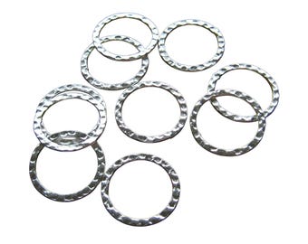 May include: A collection of eight circular metal rings with a silver-toned finish. Each ring features a distinct hammered texture along its surface, creating a series of small, reflective indentations that catch the light across the metal.