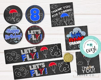 May include: Printable party decorations with a chalkboard theme. The decorations feature a blue and red color scheme with clouds, parachutes, and the text "Let's Fly!" and "Happy Birthday!"