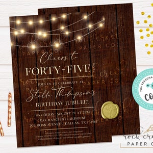 May include: A rustic wood background with string lights and the text "Cheers to Forty-Five Years" in gold lettering. The text "Stella Thompson's Birthday Jubilee!" is also included. The invitation is for a birthday party at a steakhouse on August 21st at 7pm. The invitation is editable with Corjl.