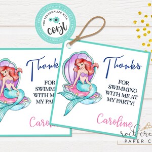 May include: Two mermaid-themed thank you tags with a watercolor illustration of Ariel from The Little Mermaid sitting on a seashell. The text on the tags reads "Thanks for swimming with me at my party!" and is personalized with the name "Caroline". The tags are teal and white with a pink and purple seashell.