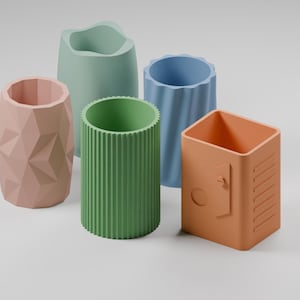 May include: A collection of five cylindrical desk organizers in various pastel colors. The set includes a pink geometric faceted holder, a light green organic shape, a green ribbed container, a blue fluted vessel, and an orange locker-style box.