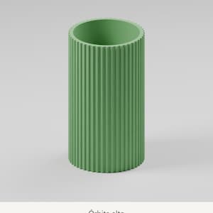 May include: A tall, cylindrical sage green vase featuring a vertically ribbed, fluted exterior texture. The object has a wide, open top and a flat base. Below the object, the text &Oacute;rbita alto is printed in a simple, dark font.