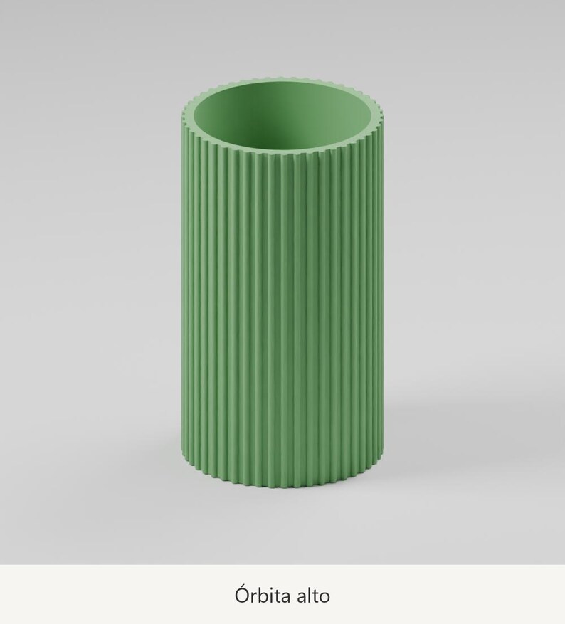 May include: A tall, cylindrical sage green vase featuring a vertically ribbed, fluted exterior texture. The object has a wide, open top and a flat base. Below the object, the text &Oacute;rbita alto is printed in a simple, dark font.