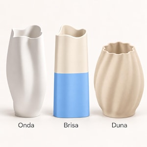 May include: Three vases labeled Onda, Brisa, and Duna. The first is a tall white vase with a wavy rim. The second is a cylindrical vase with a cream top and blue bottom. The third is a beige, rounded vase with a scalloped rim and vertical ridges.