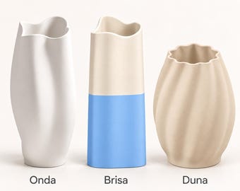 Puede incluir: Tres jarrones etiquetados como Onda, Brisa y Duna. El primero es un jarrón blanco alto con borde ondulado. El segundo es un jarrón cilíndrico con la parte superior crema y la inferior azul. El tercero es un jarrón beige redondeado.