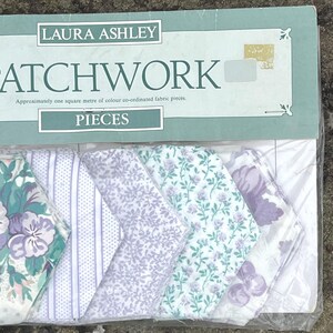 Pode incluir: Um pacote de pe&ccedil;as de tecido patchwork Laura Ashley. O pacote cont&eacute;m v&aacute;rias pe&ccedil;as de tecido com desenhos florais e estampados em tons de roxo, verde e branco. O pacote diz "PATCHWORK" e "PIECES".