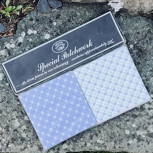 Puede incluir: Un paquete de tela de patchwork con un estampado floral en tonos azules y blancos. El embalaje dice "Special Patchwork" e incluye el texto "42 x 42cm piezas en un color". La tela está empaquetada en un envoltorio de plástico transparente.