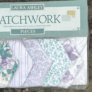 Pode incluir: Um pacote de pe&ccedil;as de tecido patchwork Laura Ashley. As pe&ccedil;as de tecido apresentam v&aacute;rios padr&otilde;es florais e listrados em tons de roxo, verde e branco. A embalagem diz "PATCHWORK" e "PIECES".