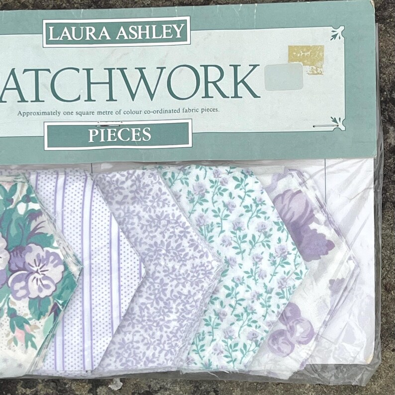 Pode incluir: Um pacote de pe&ccedil;as de tecido patchwork Laura Ashley. As pe&ccedil;as de tecido apresentam v&aacute;rios padr&otilde;es florais e listrados em tons de roxo, verde e branco. A embalagem diz "PATCHWORK" e "PIECES".