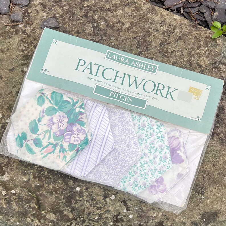 Pode incluir: Um pacote de pe&ccedil;as de tecido patchwork Laura Ashley. As pe&ccedil;as de tecido apresentam v&aacute;rios desenhos florais e estampados, incluindo branco, lavanda e verde-azulado. O pacote &eacute; selado em pl&aacute;stico transparente.