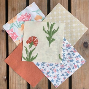 Może przedstawiać: Cztery kwadratowe kawałki tkaniny z różnymi wzorami kwiatowymi. Kwadraty są ułożone w kształt rombu. Wzory obejmują jasnoróżowy i zielony wzór kwiatowy, kremowy wzór kwiatowy z zielonymi liśćmi, kremowy wzór z siatką małych białych kwadratów oraz niebieski i różowy wzór kwiatowy.