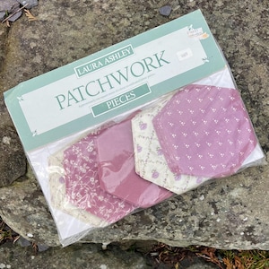May include: Laura Ashley patchwork fabric pieces in a plastic package. The fabric is a mix of pink and white floral patterns. The package says "Patchwork" and "Pieces".