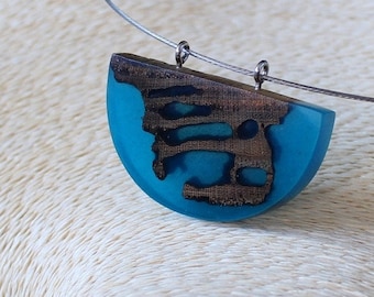 May include: A turquoise blue and brown resin pendant necklace with a silver chain. The pendant is shaped like a half-circle and has a wood grain pattern.