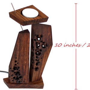 Peut inclure: Un bougeoir en bois avec un motif sculpt&eacute;. Le bougeoir mesure 26 cm de haut et a un emplacement pour une bougie chauffe-plat.