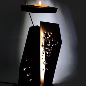 Peut inclure: Un bougeoir en bois avec un motif sculpt&eacute;. Le bougeoir a un petit sommet rond o&ugrave; une bougie peut &ecirc;tre plac&eacute;e. Le bougeoir est allum&eacute; et diffuse une lueur chaleureuse.